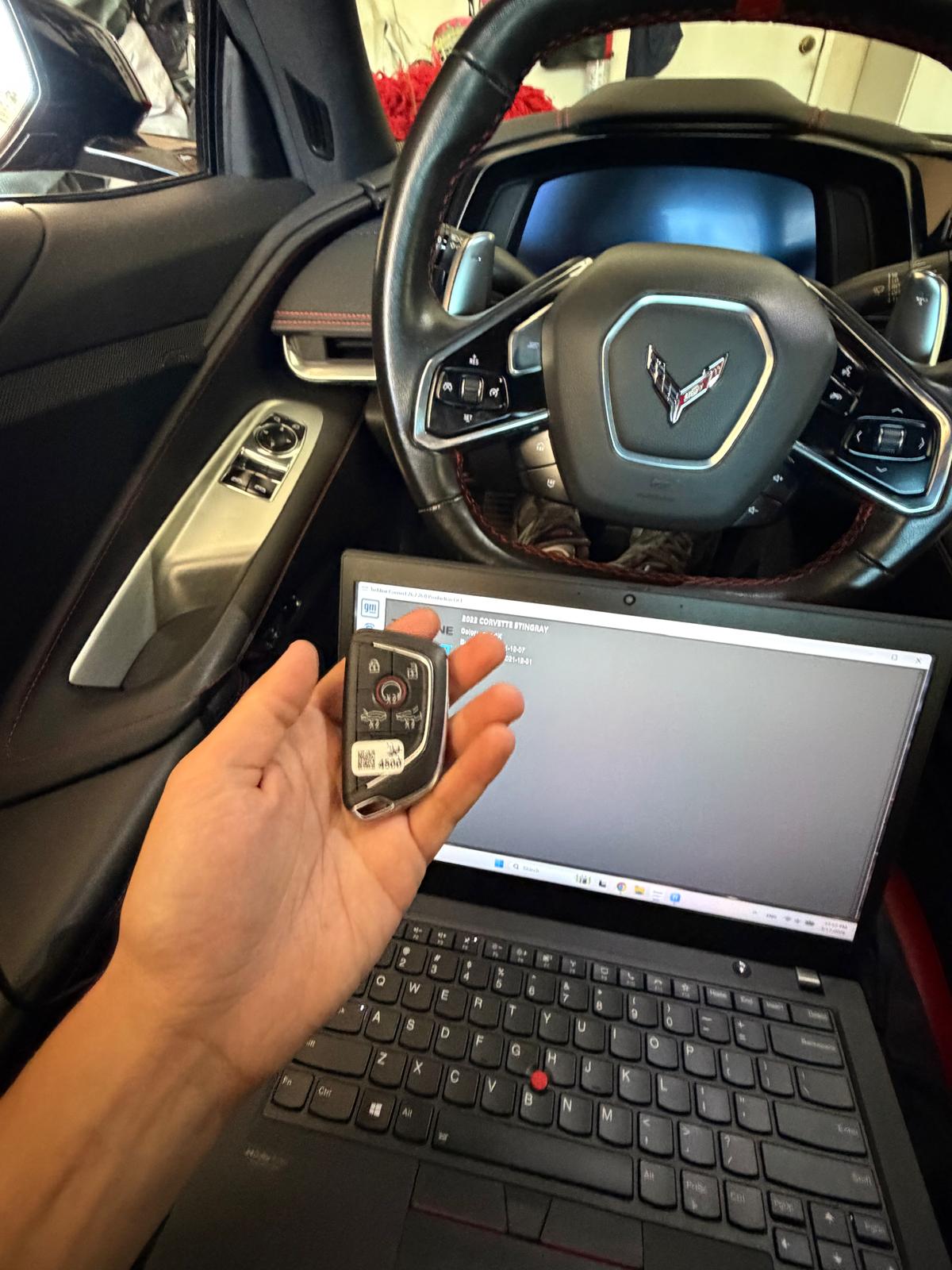 Corvette key fob alongside a programming laptop inside the vehicle